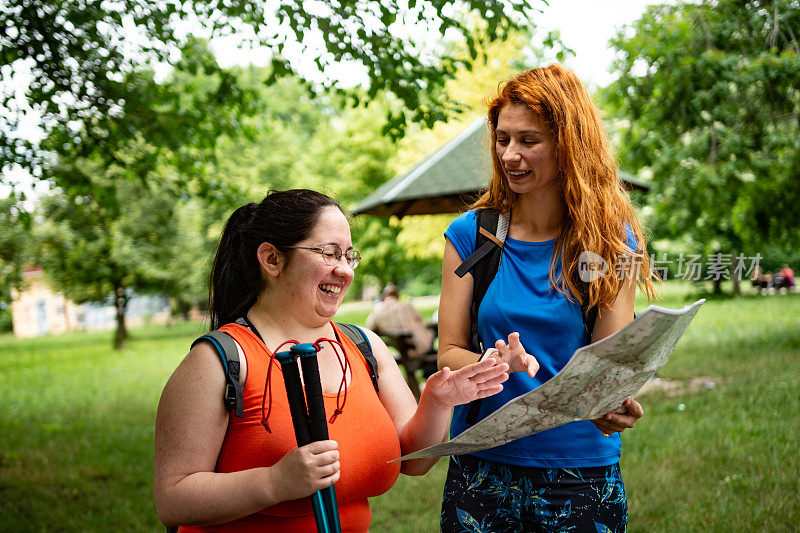 两个年轻的女人一起在大自然中徒步旅行看地图