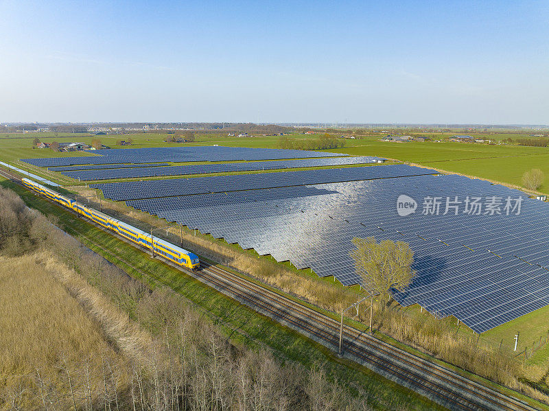 荷兰铁路公司的火车驶过一片太阳能电池板的区域