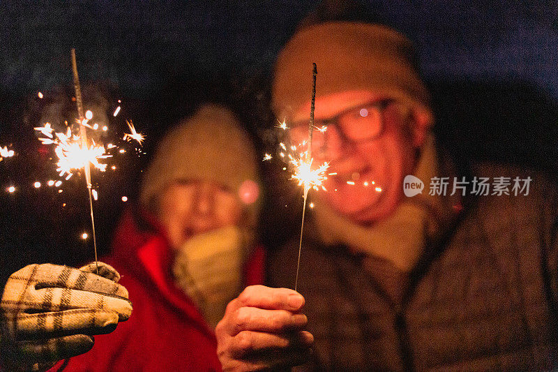 快乐的老夫妻在户外拿着烟花