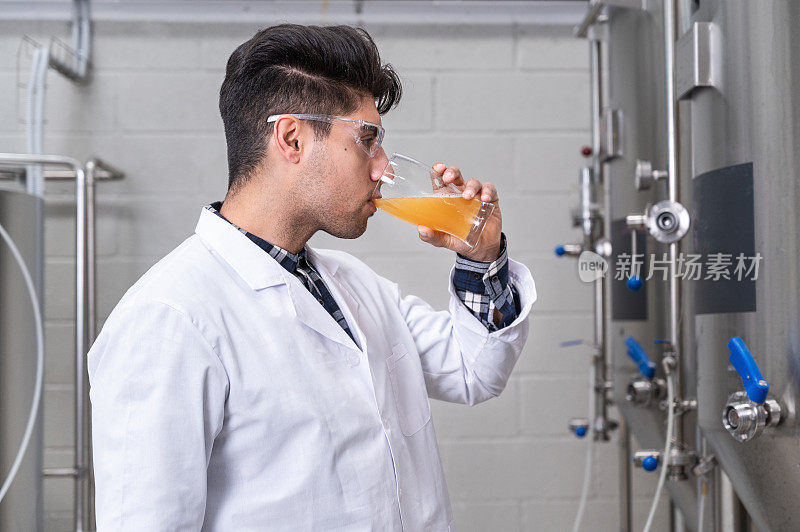 在现代啤酒厂，身穿白大褂的酿酒师在控制啤酒发酵过程。高质量的摄影。