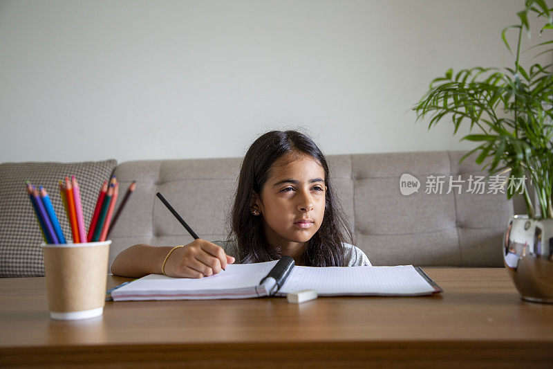 一个小女孩在家里的书桌上做作业