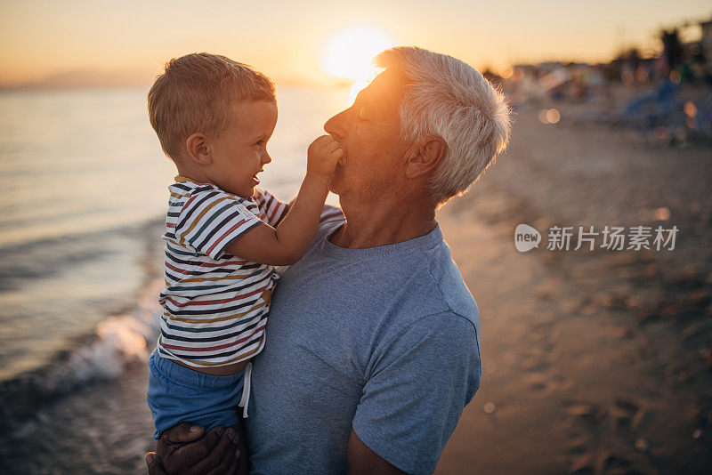 日落时分，爷爷和孙子在海滩上享受美好的一天