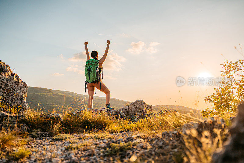 年轻的女徒步旅行者在登上山顶后欢呼