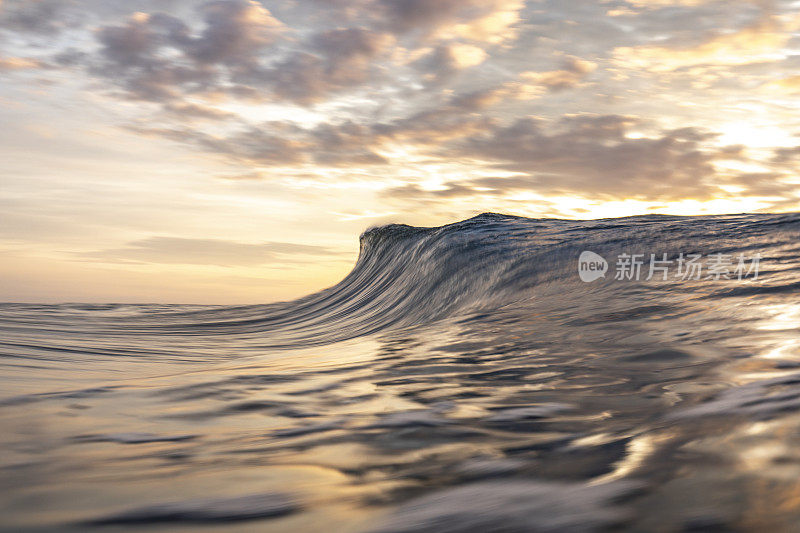 明亮的金色日落反射在海洋与大波浪形成
