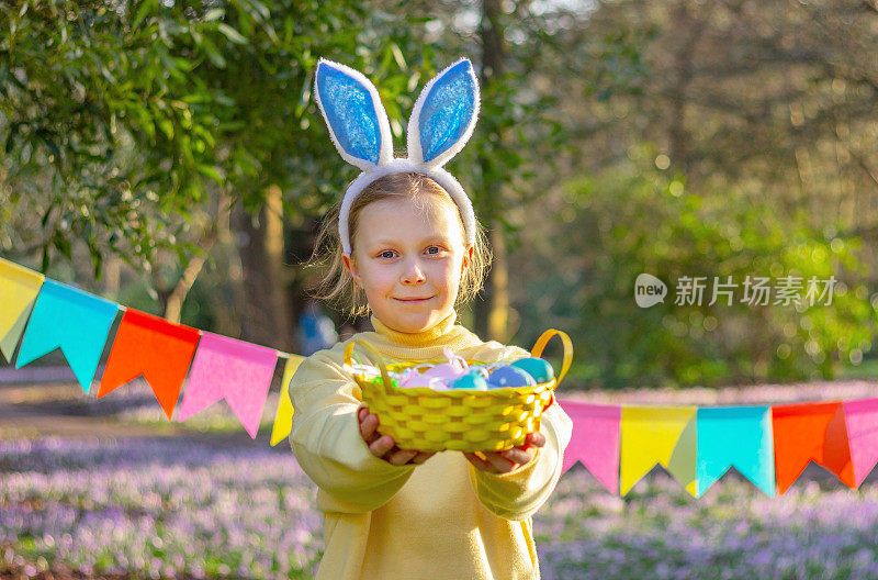 小女孩头上戴着兔子耳朵，篮子里放着复活节彩蛋
