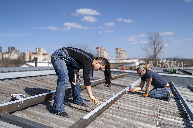 一队男女混合的工作人员正在屋顶上准备安装太阳能电池板。