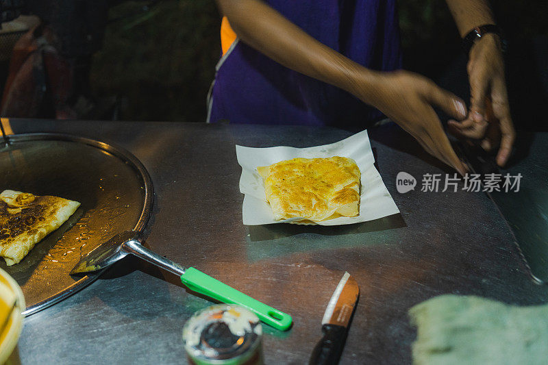 一位面目全非的男子在泰国夜市上做煎饼