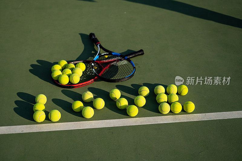 硬地上放着两个网球拍，网球横着写着爱