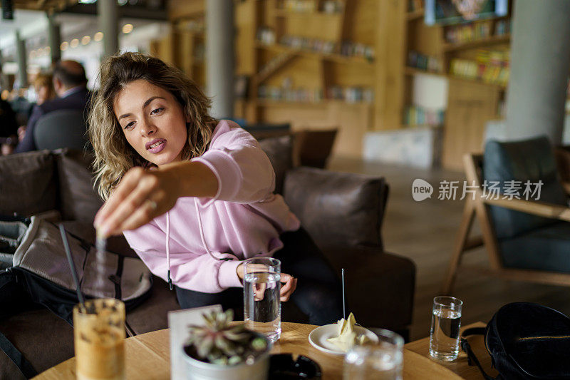 美丽的年轻女子在最喜欢的咖啡馆享受咖啡