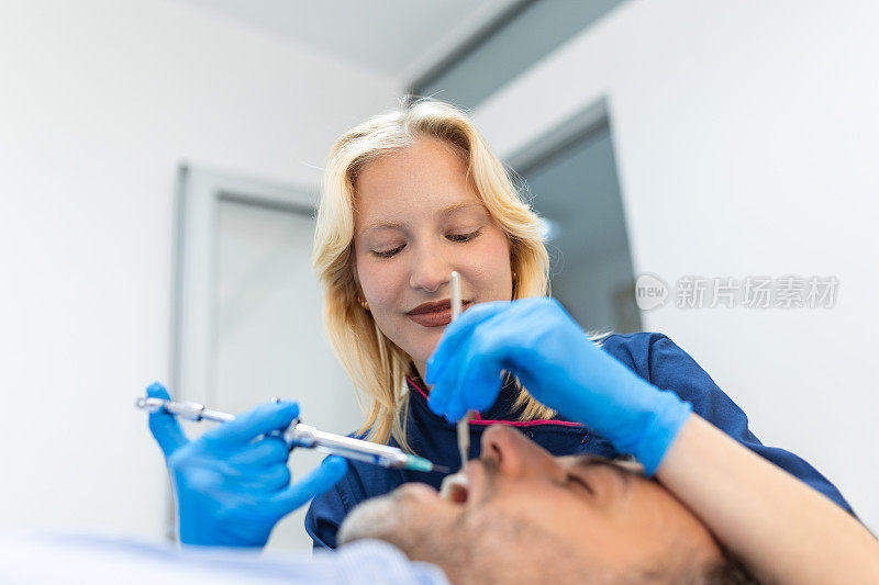 止痛药麻醉注射。牙医在现代牙科诊所检查病人的牙齿。特写裁剪图片与copyspace。穿蓝色制服的女医生。