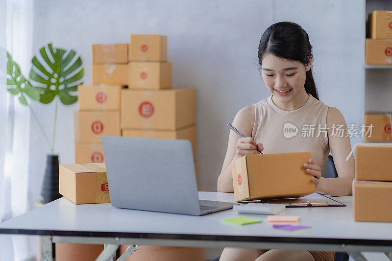 迷人的亚洲女人开始一个小生意，中小企业企业家，配送仓库与邮箱。业主的小型家庭办公室在线营销和产品包装及送货上门服务。