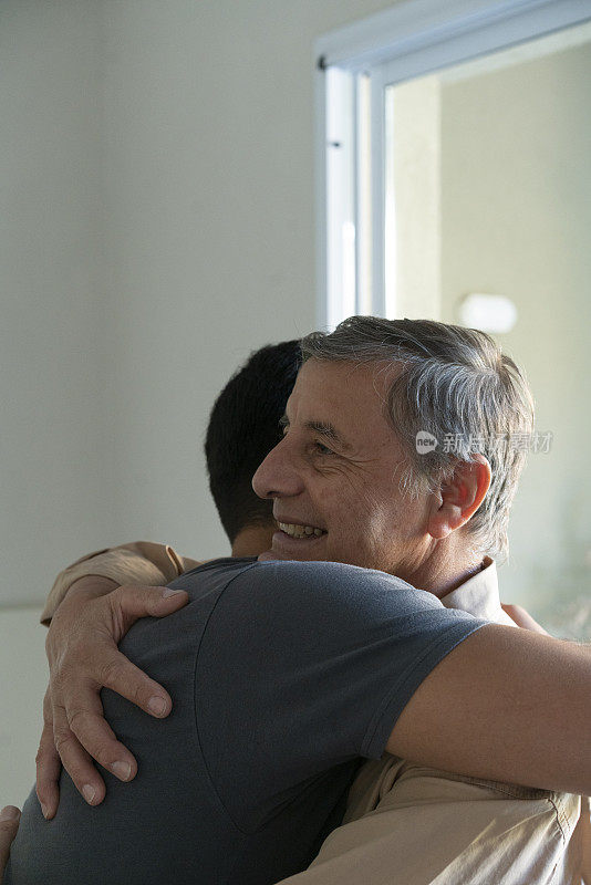 父亲和年幼的儿子在家中客厅拥抱，表达支持和理解