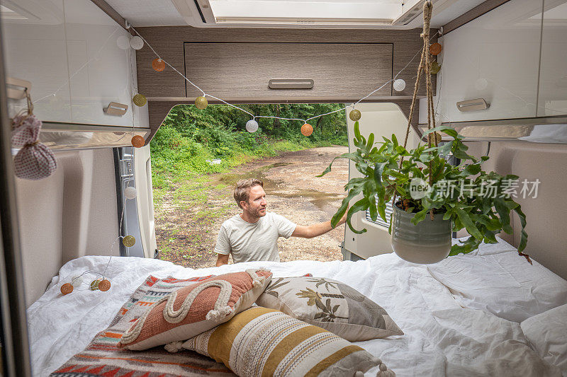 一个人早上在他的露营车里整理他的床
