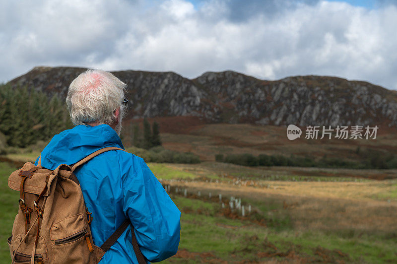 一位退休老人在看苏格兰的乡村风光