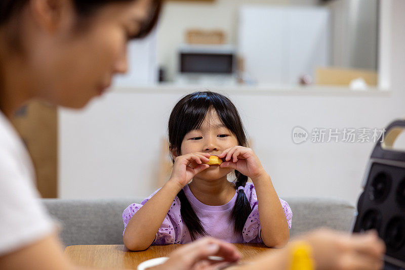 母女俩在家里吃着自制的饼干