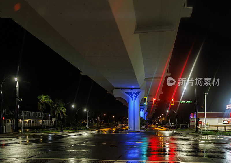 飓风夜驾驶边缘:站在潮湿的街道在夜间照明立交桥道路。飓风过后，佛罗里达州坦帕市。软焦点