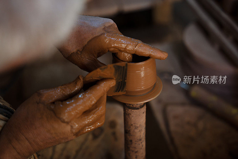 一位老人正在制作一个陶杯