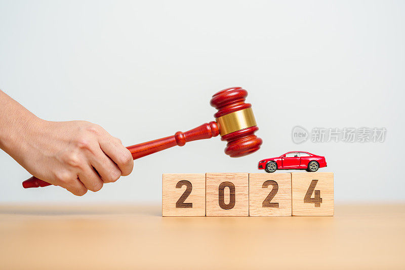 汽车法，保险，汽车税，拍卖和投标概念。2024年，法院的桌子上有法官的小木槌，上面有撞坏的小玩具汽车模型。