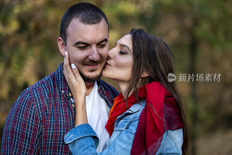 一对年轻夫妇在秋天的公园里接吻。