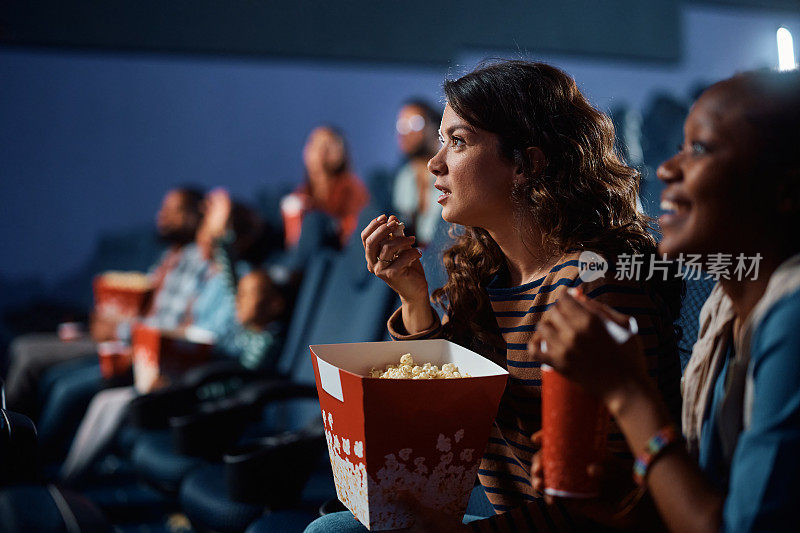 年轻女子在电影院边看悬疑电影边吃爆米花。