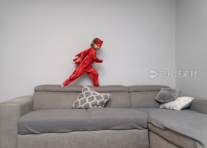 可爱的小女孩穿着红色的超级英雄装在公寓里跑来跑去，只是玩得开心，拯救了一天