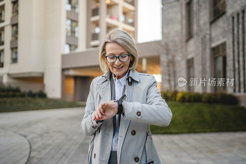 一名女子成熟女站在城市户外使用智能手表