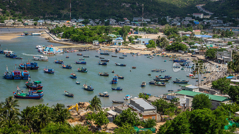 站在渔船和旅游船前，在越南宁顺清澈的蓝色海水下，紧挨着