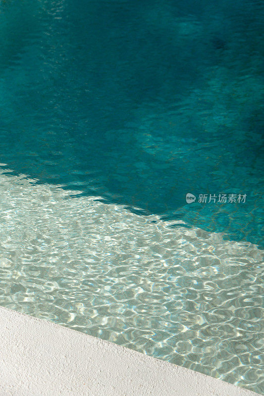 游泳池边缘与绿松石瓷砖和水面上的阳光