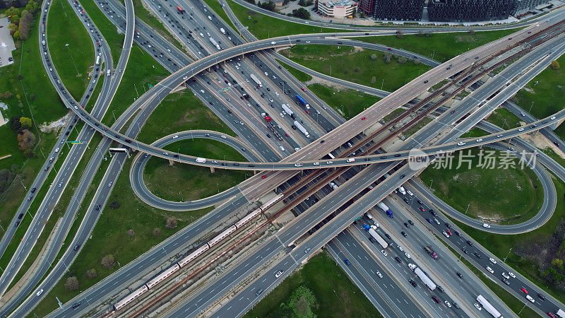 鸟瞰城市公路迷宫，汽车穿梭于复杂的立交桥，展示交通效率。无人机拍摄车辆在错综复杂的道路上，现代城市通勤动态的亮点。