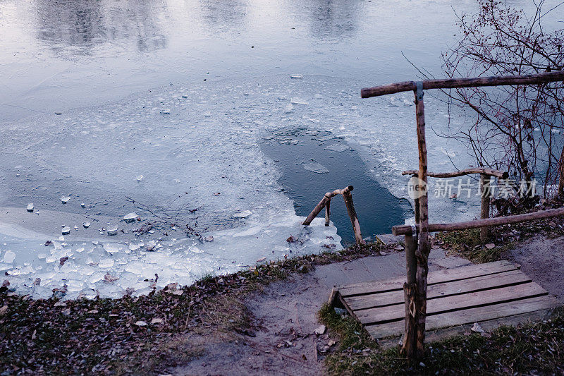 冰上游泳的地方在河与木台阶和栏杆。寒冷的雪湖或河景。冬季景观