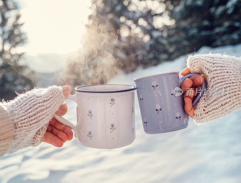 在冬天的森林空地上，男人和女人双手编织手套，端着热茶
