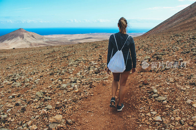 年轻女子徒步旅行与全景火山