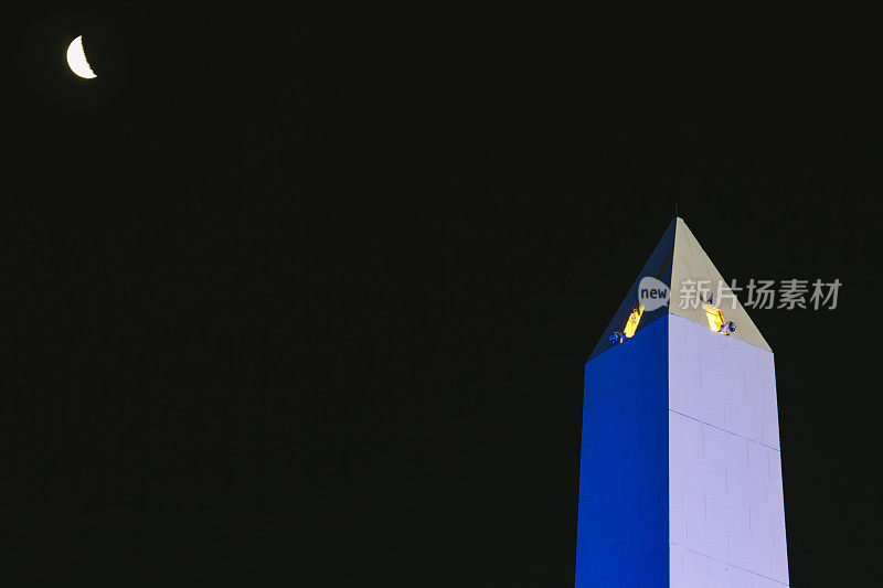 布宜诺斯艾利斯方尖碑的尖端在夜晚被照亮的蓝色旁边的半月
