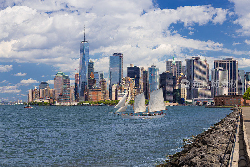 曼哈顿金融区，总督岛，帆船(高船)，史坦顿岛渡轮码头，纽约港的水，世界贸易中心和蓝天。