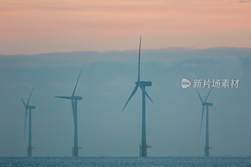 可持续的资源。有雾的早晨风力发电厂的涡轮机。海上柔和的日出。