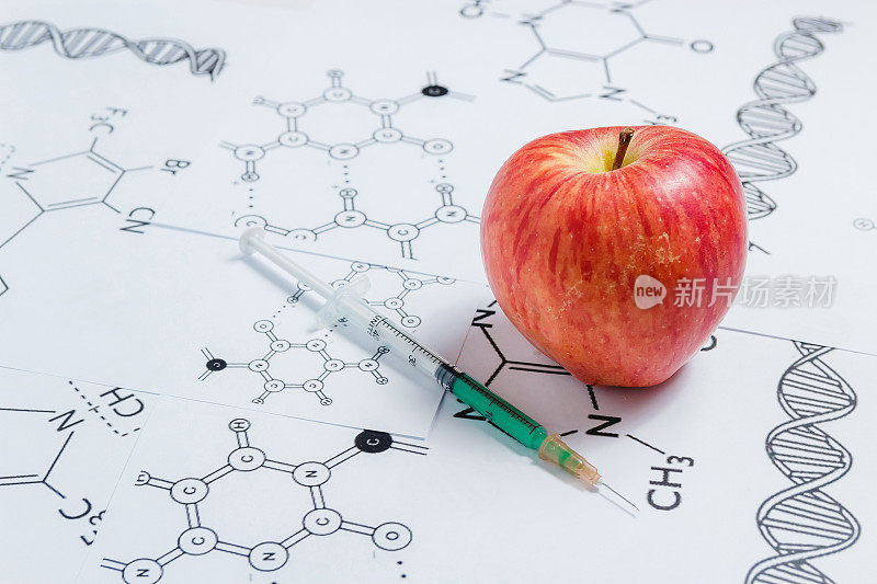 非天然产品、转基因的概念。注射器和红苹果在白色背景和化学配方，