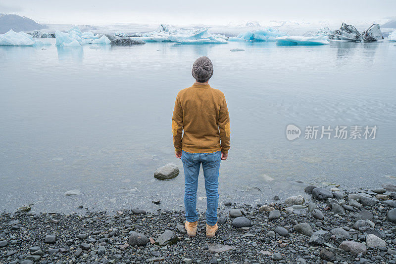 游客男性看冰川泻湖与冰山漂浮在湖上，冰岛旅游夏季概念