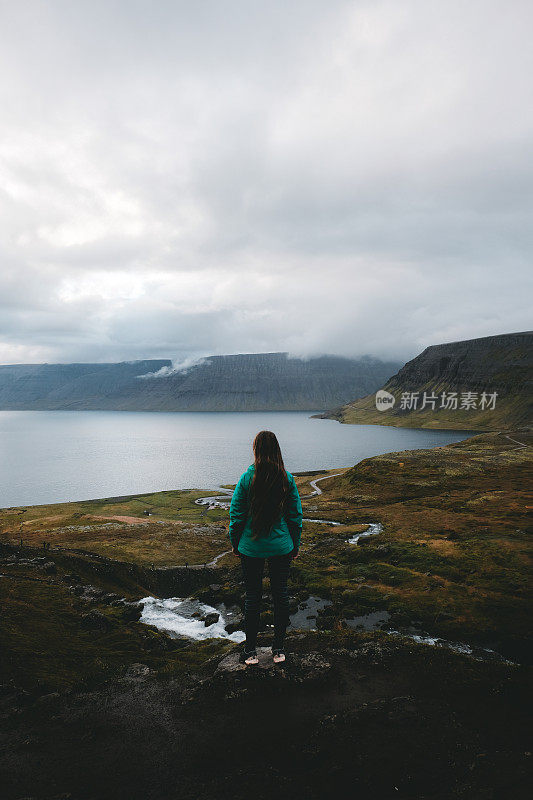 长头发的女人在看冰岛峡湾和山脉的美景