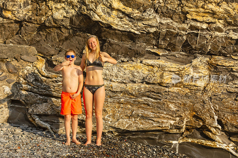 金发女孩和男孩在夏天的海滩上摆姿势