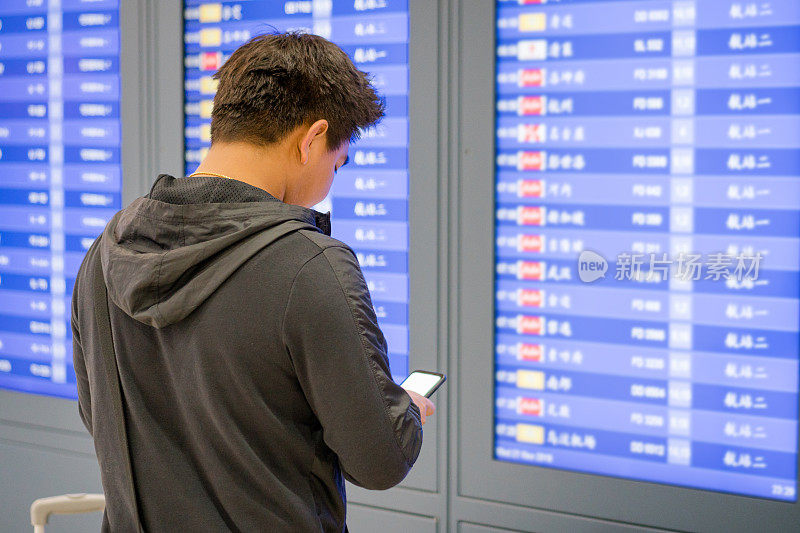 年轻亚洲旅客在机场离港大厅的自助值机处。