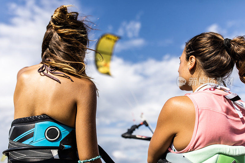 后视图的妇女准备风筝冲浪在夏天的一天。