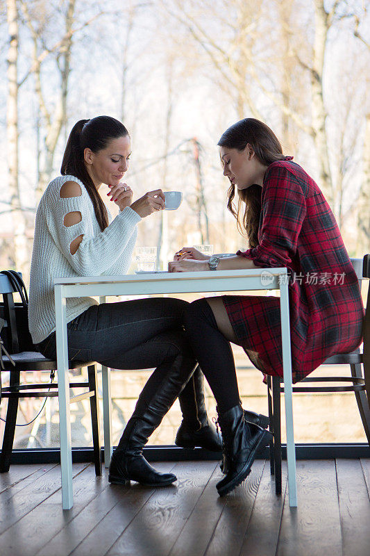 两个女孩在喝咖啡休息。