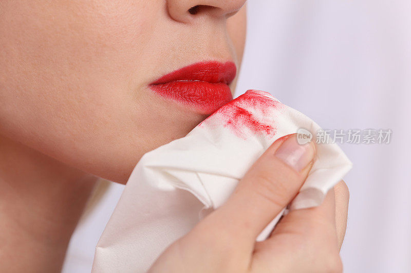 用清洁液卸妆的女人。白色餐巾纸上的红色口红印