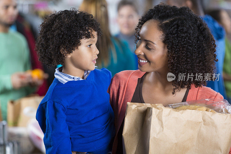 母亲和年幼的儿子接受食品银行的食品捐赠