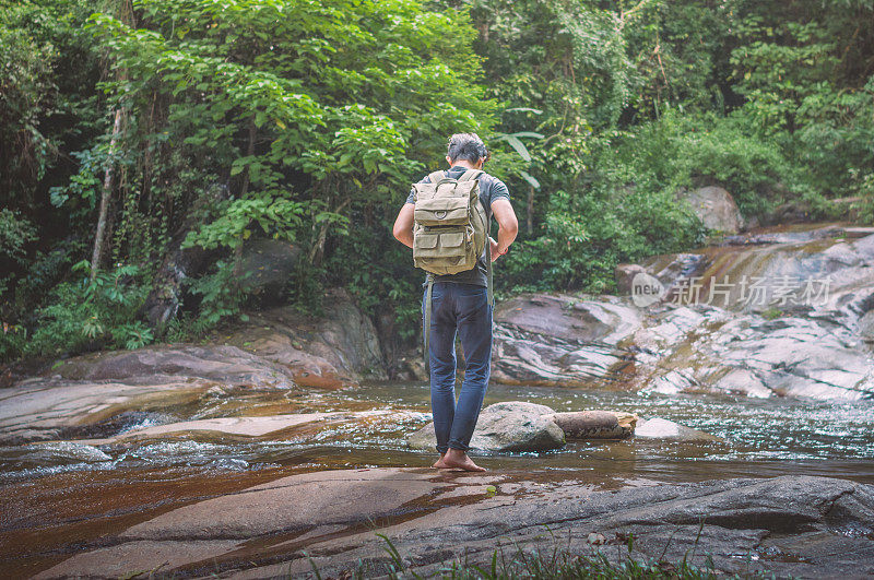 徒步旅行者背包和笔记本电脑和手机在瀑布森林。