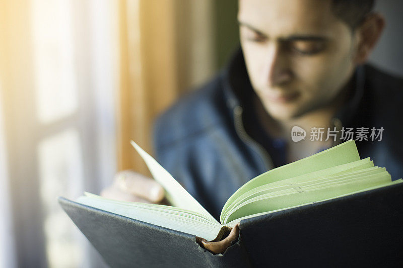 年轻人在家里学习，注意力集中在书本上。