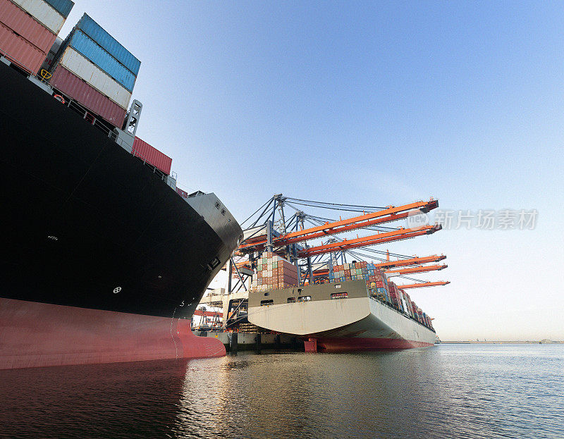 日出时分在港口装载货物的集装箱船