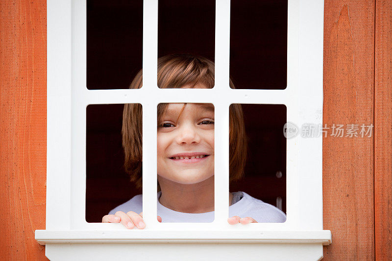 微笑的四岁男孩透过窗户偷看