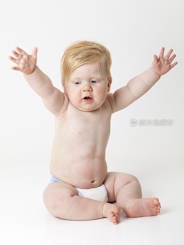 可爱的胖乎乎的婴儿，穿着尿布，双臂高举