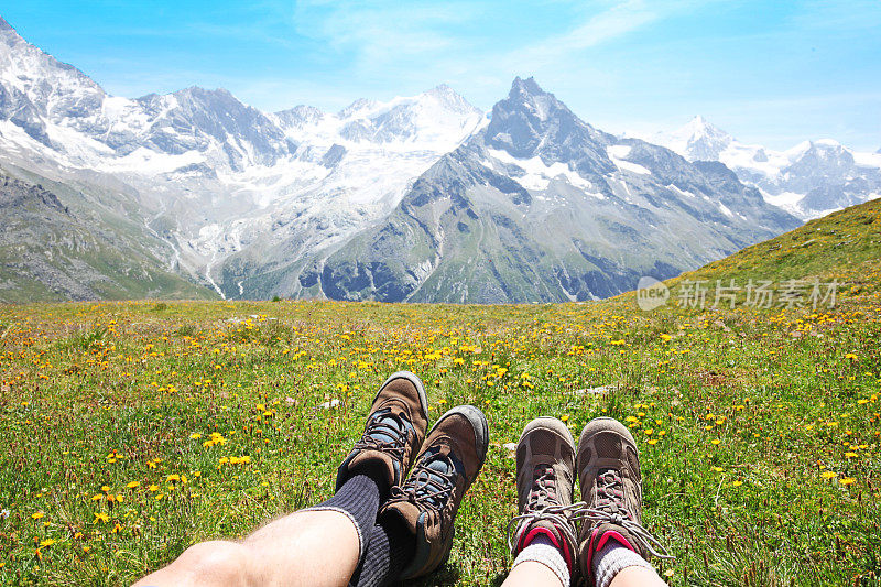 两个徒步旅行者躺在瑞士山脉的野花草地上